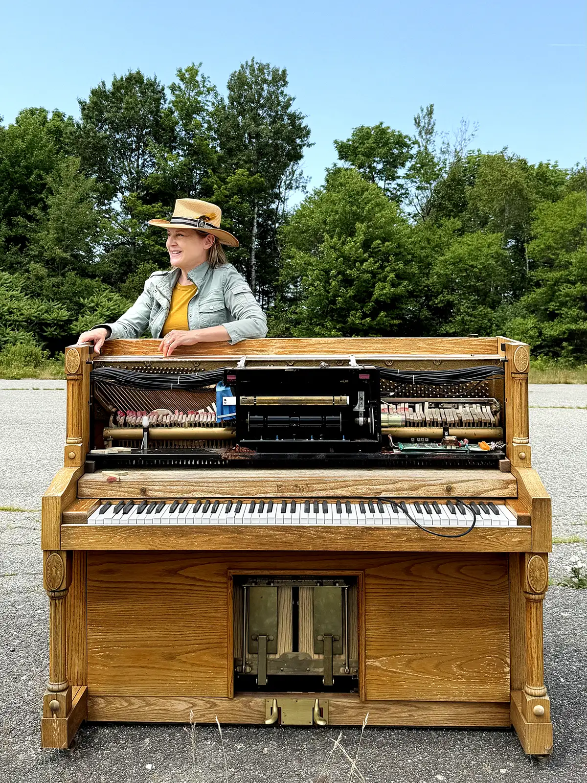 Denise Chastain standing behind an open upright piano outdoors